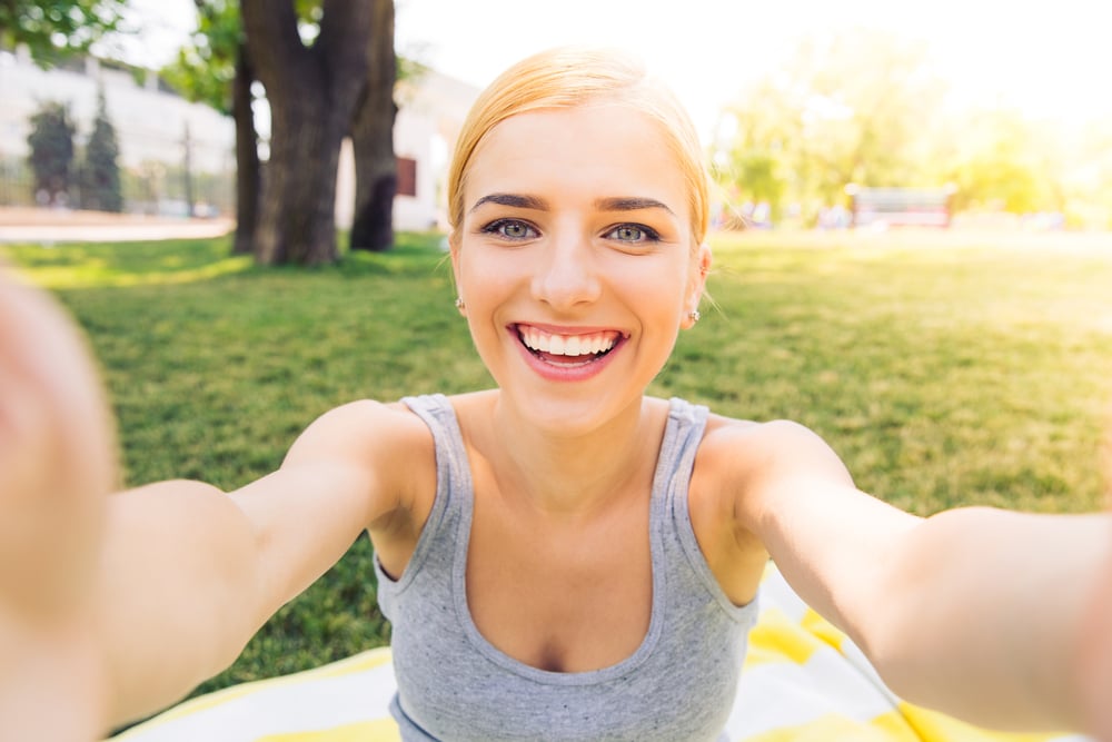 POrtrait of a smiling young girl making selfie photo in park